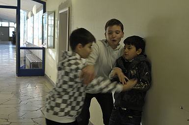 Zwei Jungen prügeln sich. Ein Dritter treibt die beiden auseinander.