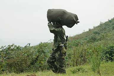 Soldat in Tarnkleidung einen Sack tragend.
