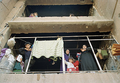 IDPs Familien schauen aus kaputtem Haus herab