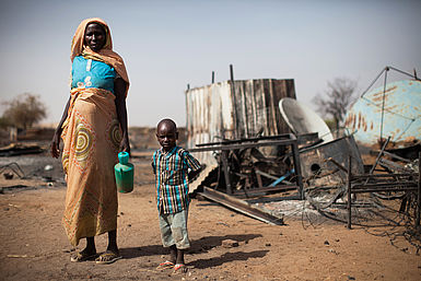 Eine Mutter mit ihrem Sohn vor den Ruinen ihres zerstörten Hauses