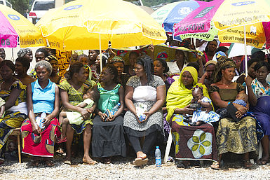 Nigerianische Frauen sitzen unter Sonnenschirmen
