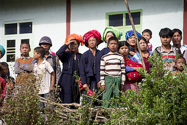 Dorfbewohner in Myanmar stehen vor einem Haus.